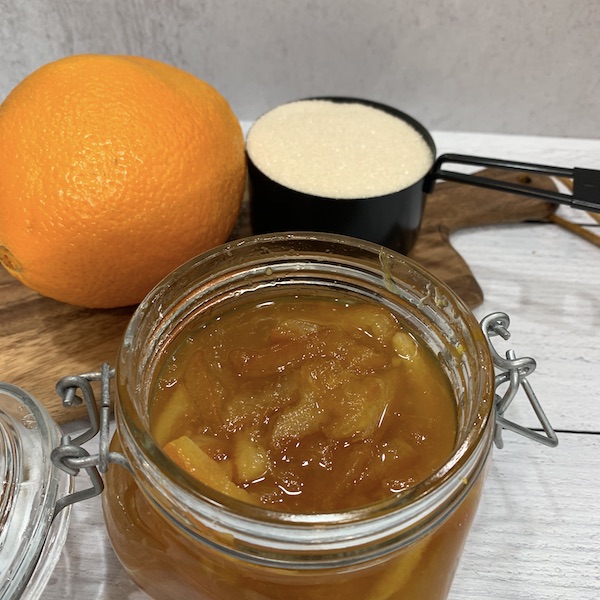 vegan two ingredient instant pot orange marmalade without pectin in a weck jar with an orange and caster sugar in a measuring cup behind it